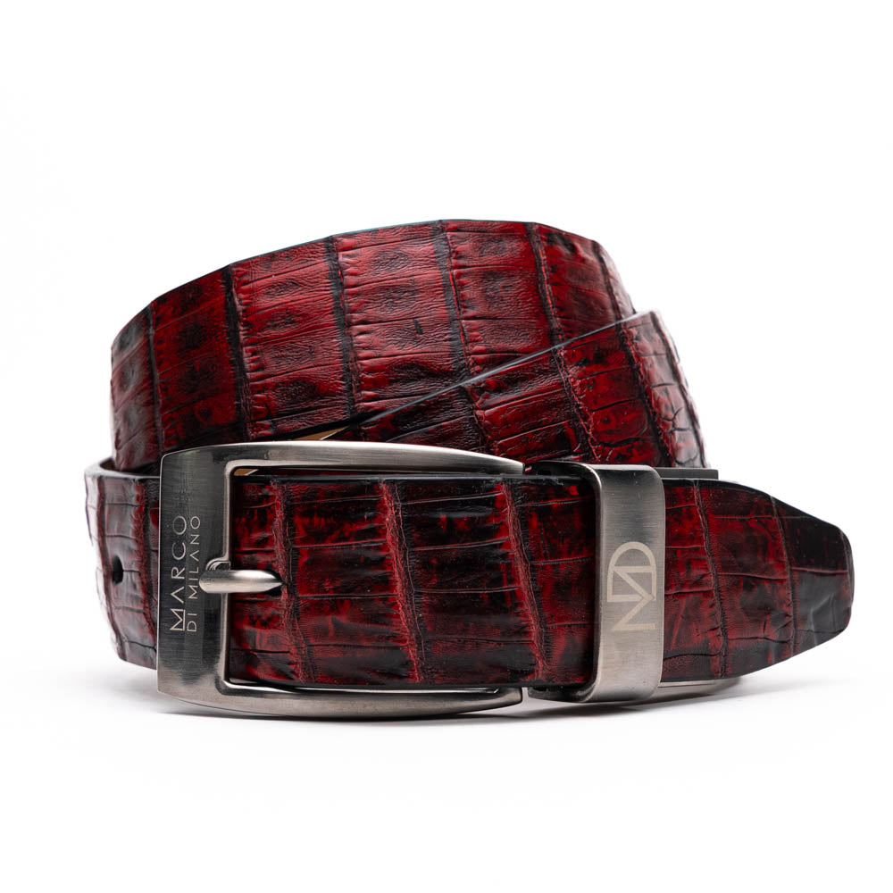 The Riccardo Belt Black Cherry by Marco Di Milano is a genuine caiman fuscus-belly belt in red and black, featuring a silver buckle engraved with the brand’s logo—perfect for lovers of fine exotics.