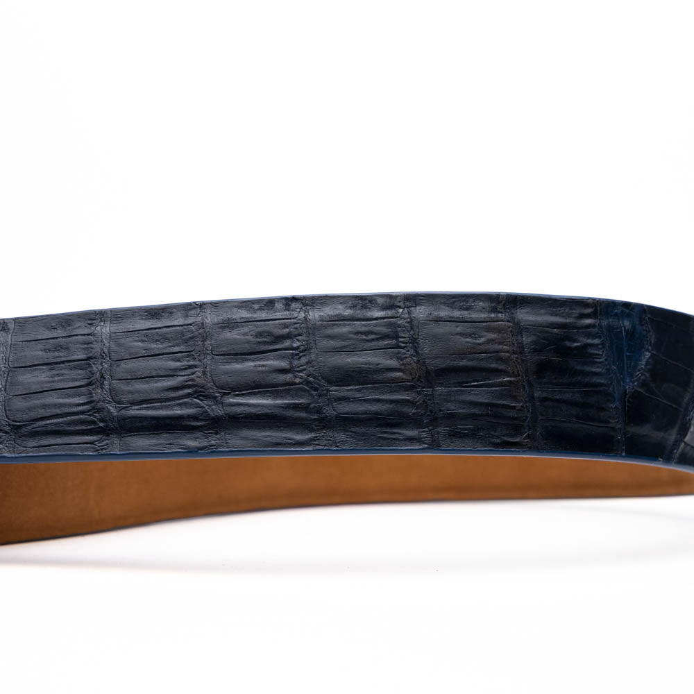The Riccardo Belt Navy by Marco Di Milano features genuine exotic leather with a crocodile pattern, a dark blue finish, and a silver buckle with engraved branding and initials.