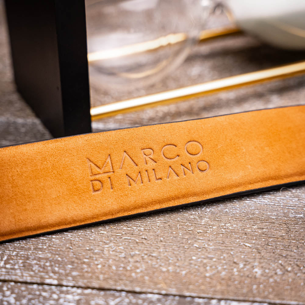 The Riccardo Belt Oil Orix by Marco Di Milano features genuine exotic leather with a crocodile pattern, a silver engraved buckle, and brand logos—elegantly coiled on a white background.