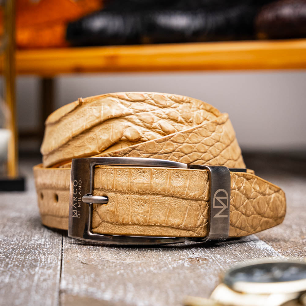 The Riccardo Belt Orix by Marco Di Milano is a rolled tan caiman fuscus-belly belt with an engraved silver buckle, shown on a white background—a genuine exotic accessory.