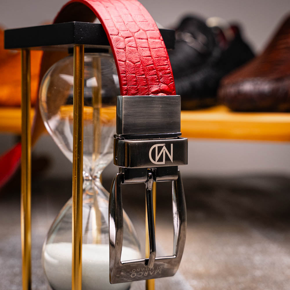 The Riccardo Belt Red by Marco Di Milano, crafted from genuine caiman fuscus-belly leather with a crocodile texture and a silver engraved buckle, is elegantly displayed coiled on a white background—perfect for refined style.