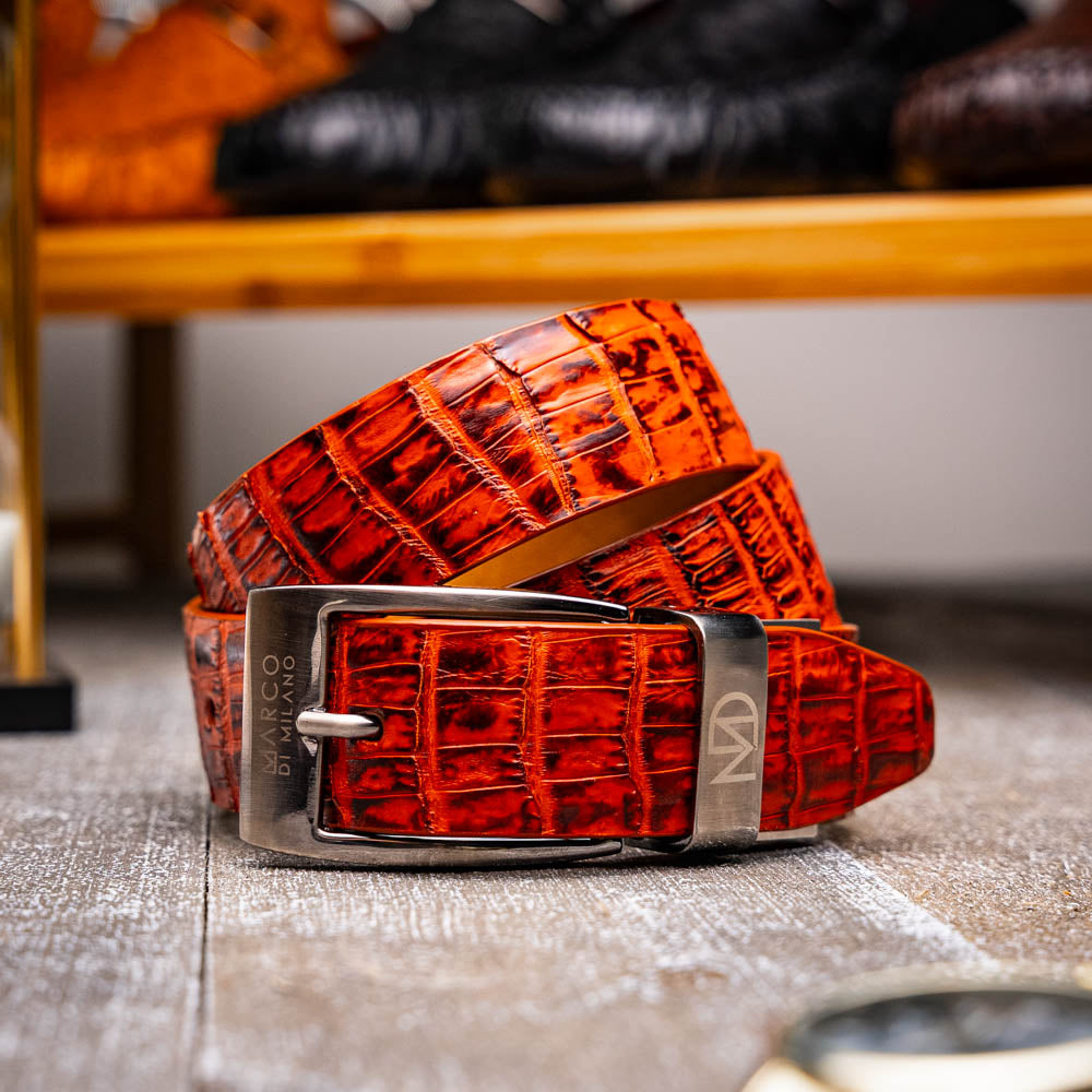 The Riccardo Belt Rustic Cognac by Marco Di Milano features a crocodile-patterned brown caiman fuscus-belly, a silver buckle, and genuine exotic leather—an ideal complement to luxury footwear.