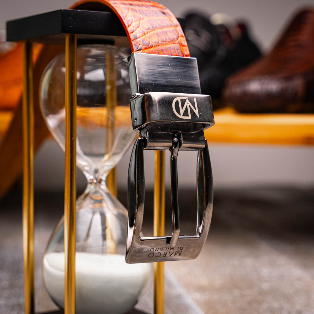 The Riccardo Belt Rustic Cognac by Marco Di Milano features a crocodile-patterned brown caiman fuscus-belly, a silver buckle, and genuine exotic leather—an ideal complement to luxury footwear.