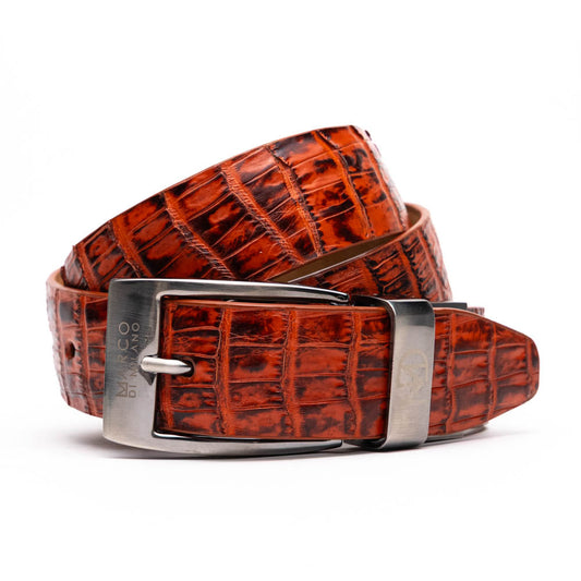 The Riccardo Belt Rustic Cognac by Marco Di Milano features a crocodile-patterned brown caiman fuscus-belly, a silver buckle, and genuine exotic leather—an ideal complement to luxury footwear.
