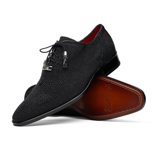 A pair of Rimini Black luxury dress shoes by Marco Di Milano, featuring a black textured finish and lace-up closure—one shoe displayed upright while the other shows the brown leather sole with embossed branding.