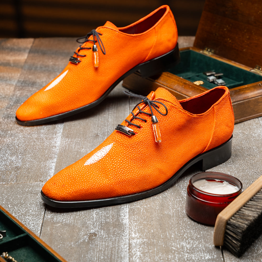 Rimini Orange men’s exotic lace-up dress shoes by Marco Di Milano, expertly crafted from genuine stingray leather in a bright orange hue with black laces; one shoe stands upright while the other lies on its side, showcasing the vibrant red sole and contrasting black heel.