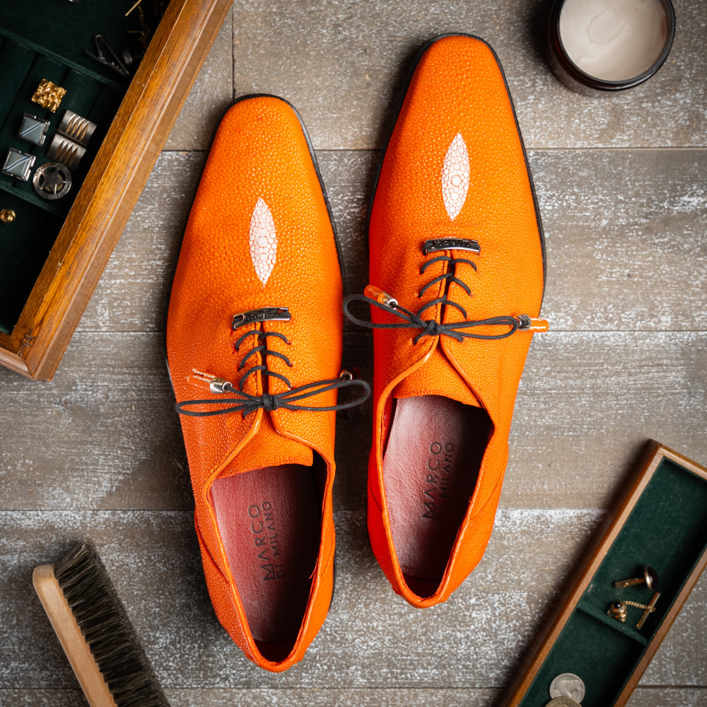 Rimini Orange men’s exotic lace-up dress shoes by Marco Di Milano, expertly crafted from genuine stingray leather in a bright orange hue with black laces; one shoe stands upright while the other lies on its side, showcasing the vibrant red sole and contrasting black heel.