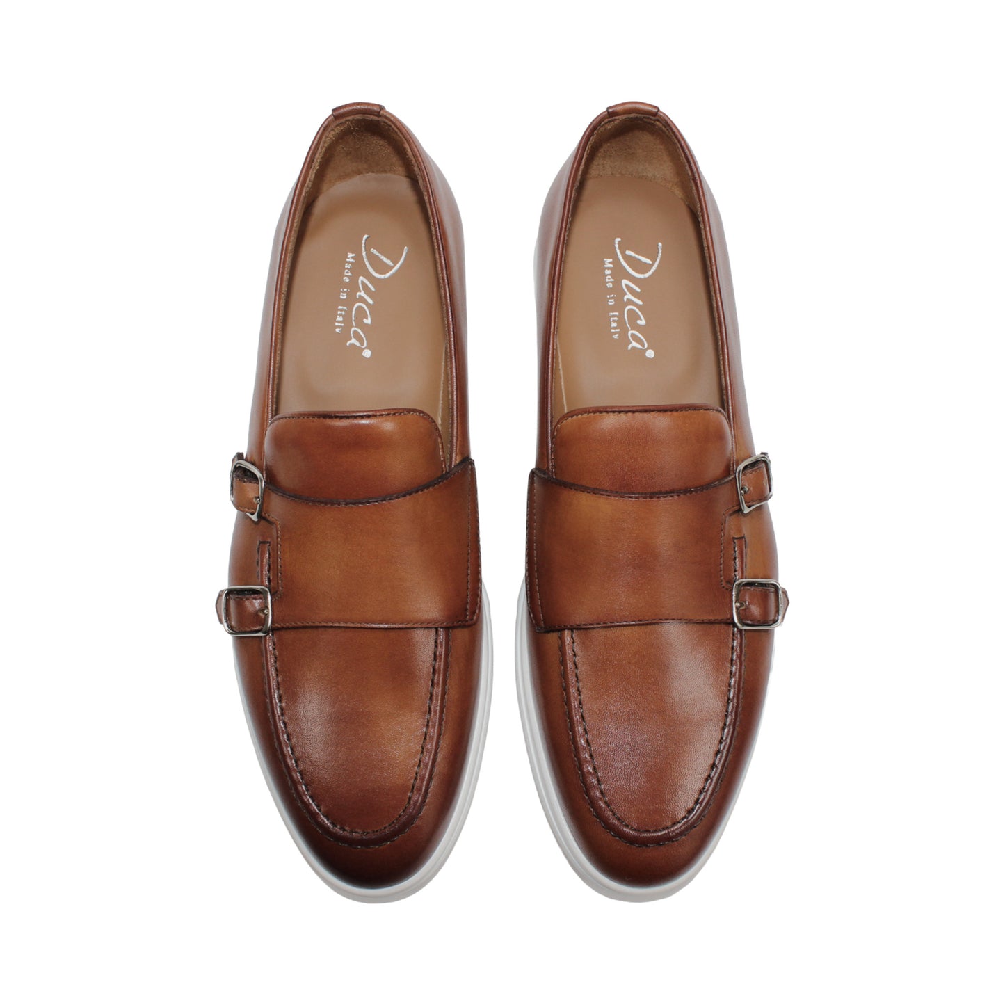 The Duca Di Matiste Duca Rimini Cognac is a brown premium calf leather loafer with metal buckle details and a white rubber sole, showcasing timeless sophistication in its side profile against a plain white background.