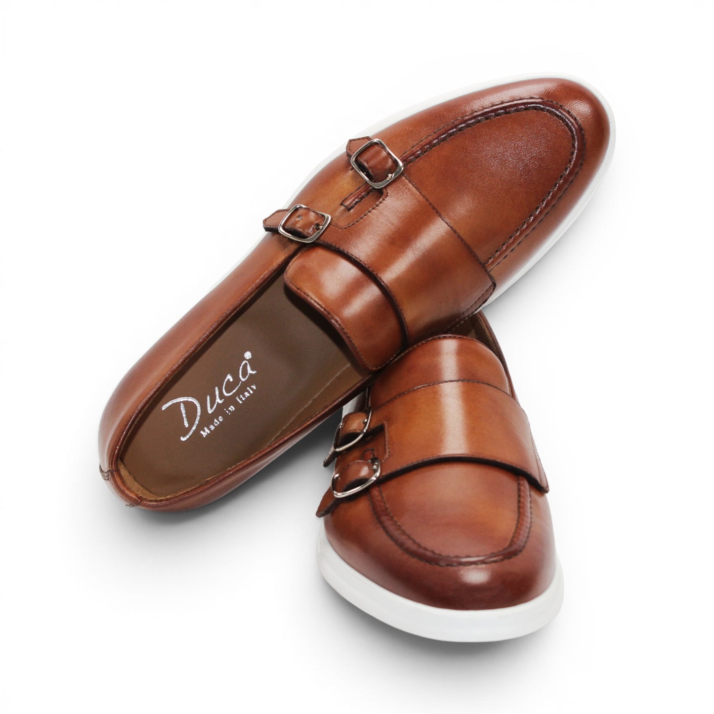 The Duca Di Matiste Duca Rimini Cognac is a brown premium calf leather loafer with metal buckle details and a white rubber sole, showcasing timeless sophistication in its side profile against a plain white background.