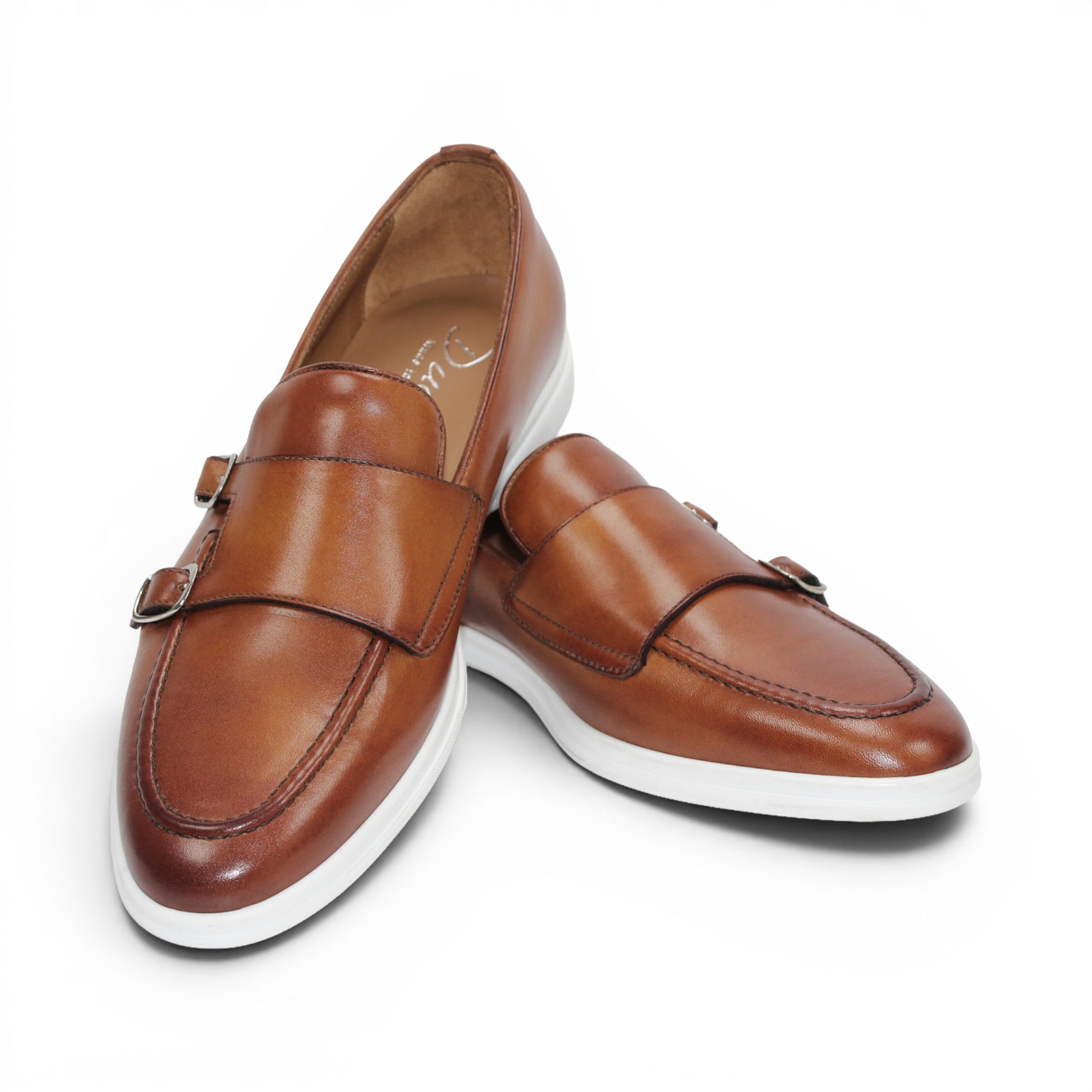 The Duca Di Matiste Duca Rimini Cognac is a brown premium calf leather loafer with metal buckle details and a white rubber sole, showcasing timeless sophistication in its side profile against a plain white background.