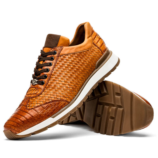 The Roma Brandy sneakers by Marco Di Milano feature brown woven calfskin, textured toe and heel, black laces, white midsoles, and brown rubber outsoles. One shoe stands upright while the other lies on its side.