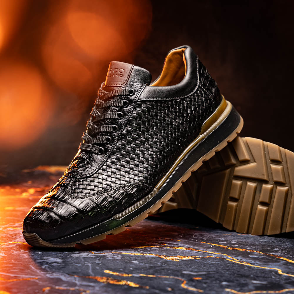 The Marco Di Milano Roma Black features luxury black woven calfskin sneakers with black laces and brown rubber soles—one shoe stands upright while the other leans against it.