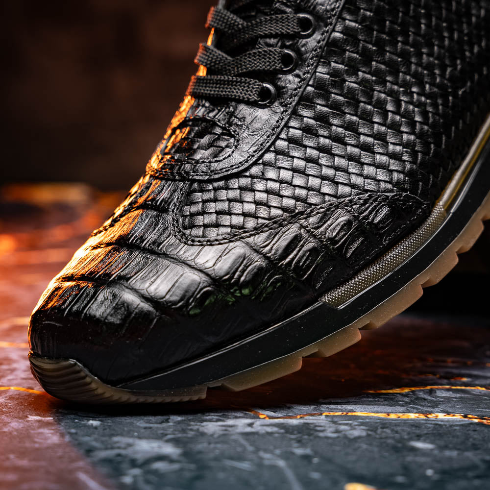 The Marco Di Milano Roma Black features luxury black woven calfskin sneakers with black laces and brown rubber soles—one shoe stands upright while the other leans against it.