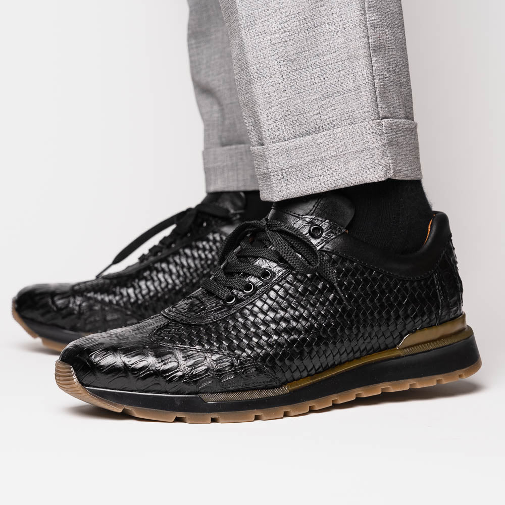 The Marco Di Milano Roma Black features luxury black woven calfskin sneakers with black laces and brown rubber soles—one shoe stands upright while the other leans against it.