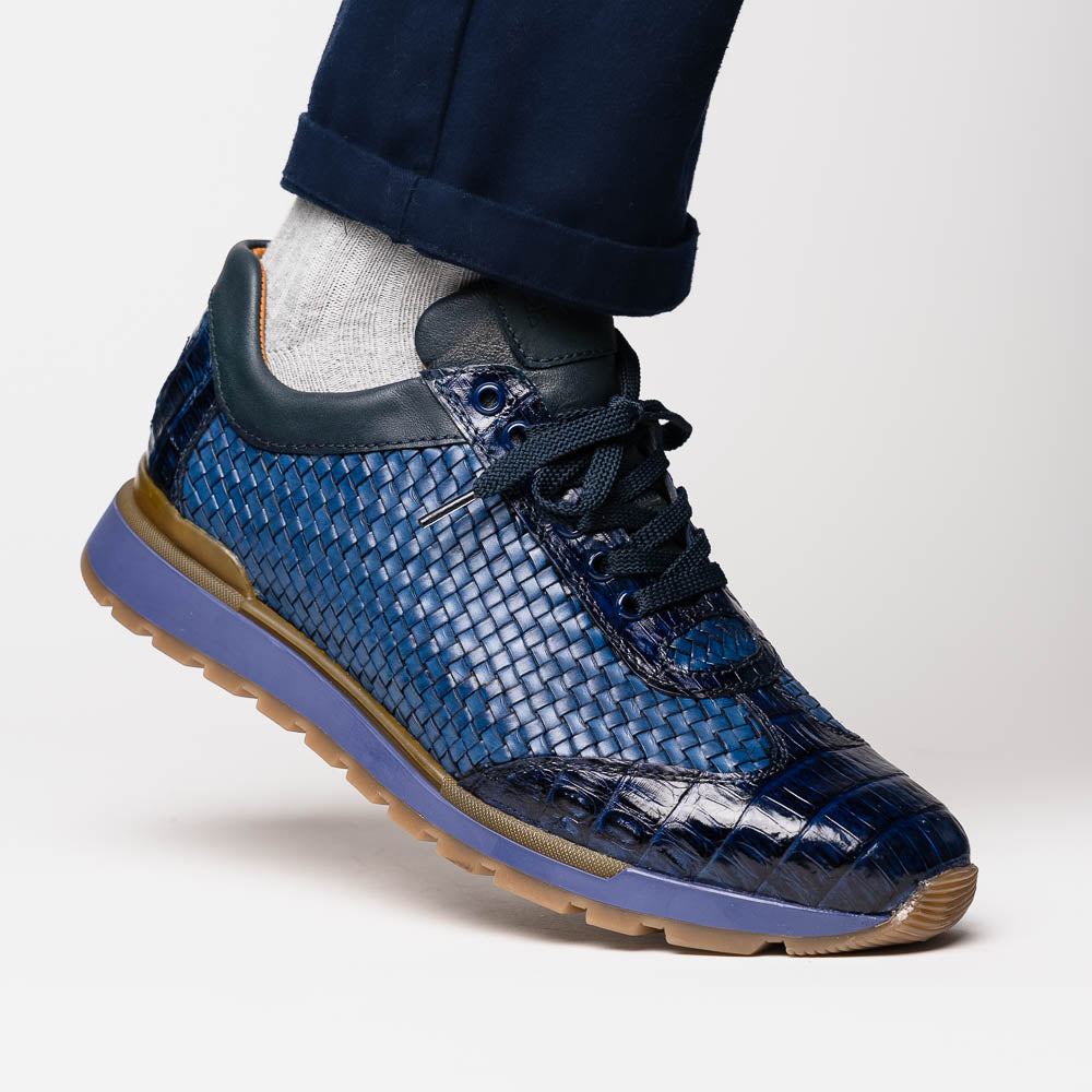 A pair of Marco Di Milano's Roma Navy sneakers: blue woven calfskin with brown rubber soles, one upright and the other leaning, highlighting the distinct tread pattern in elegant style.
