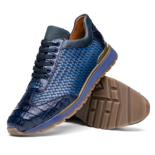 A pair of Marco Di Milano's Roma Navy sneakers: blue woven calfskin with brown rubber soles, one upright and the other leaning, highlighting the distinct tread pattern in elegant style.