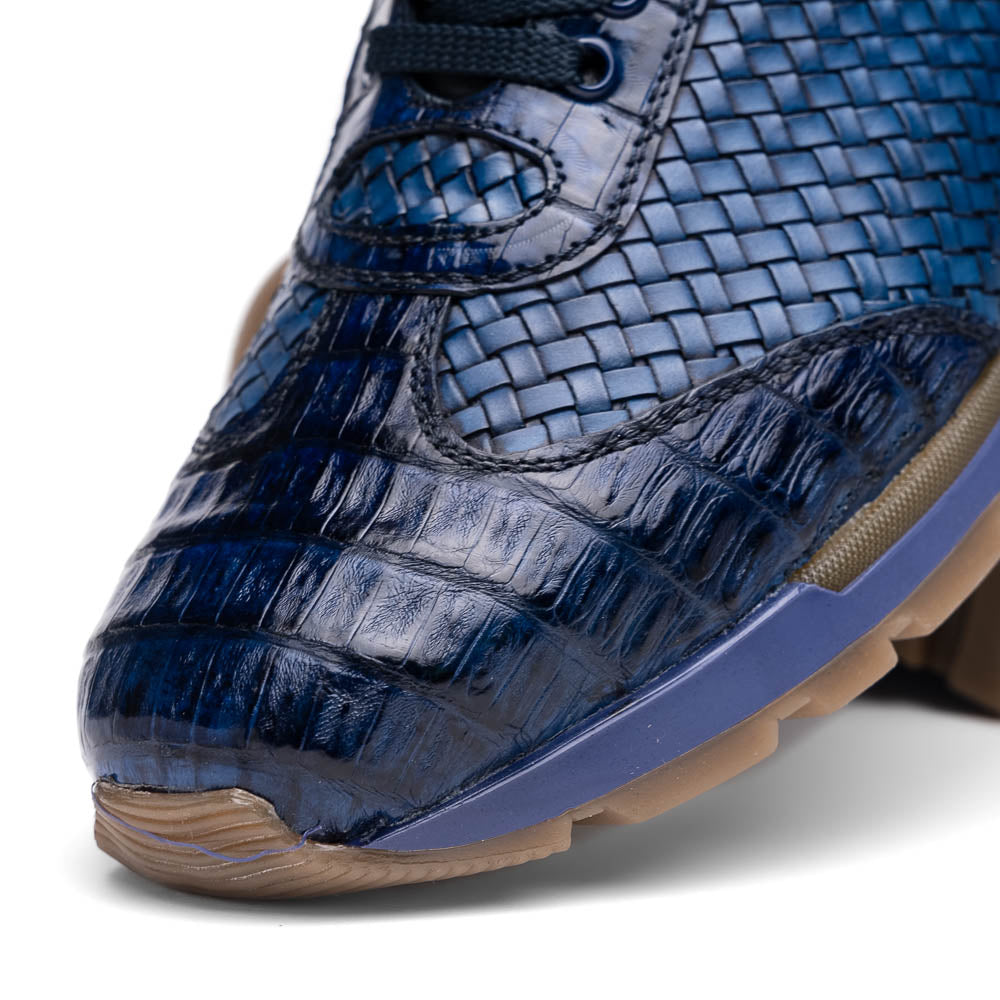 A pair of Marco Di Milano's Roma Navy sneakers: blue woven calfskin with brown rubber soles, one upright and the other leaning, highlighting the distinct tread pattern in elegant style.