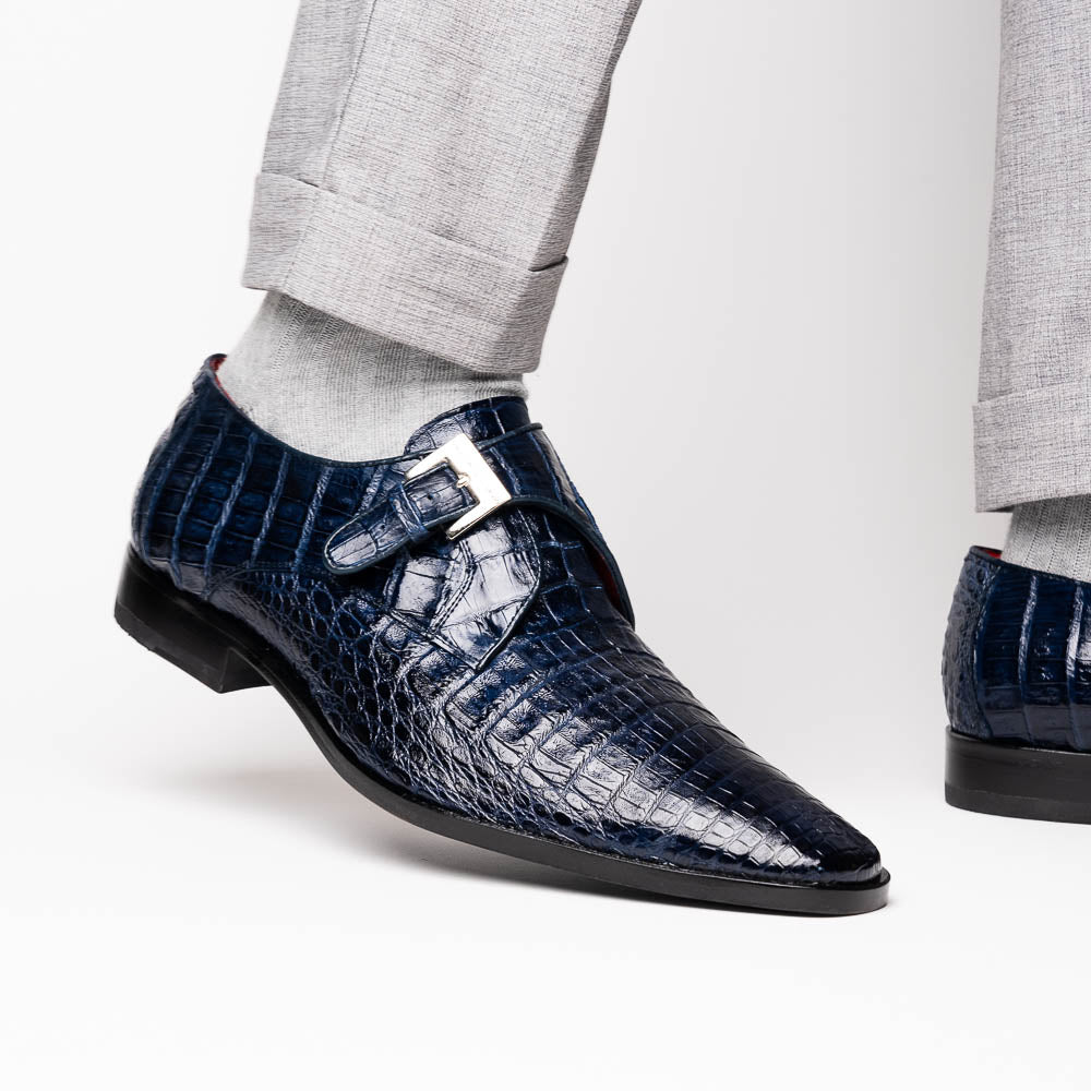 The Marco Di Milano Rovigo Navy features dark blue genuine caiman crocodile monk strap dress shoes with a silver buckle—one upright, the other on its side to display the sole—ideal for luxury men's footwear enthusiasts.