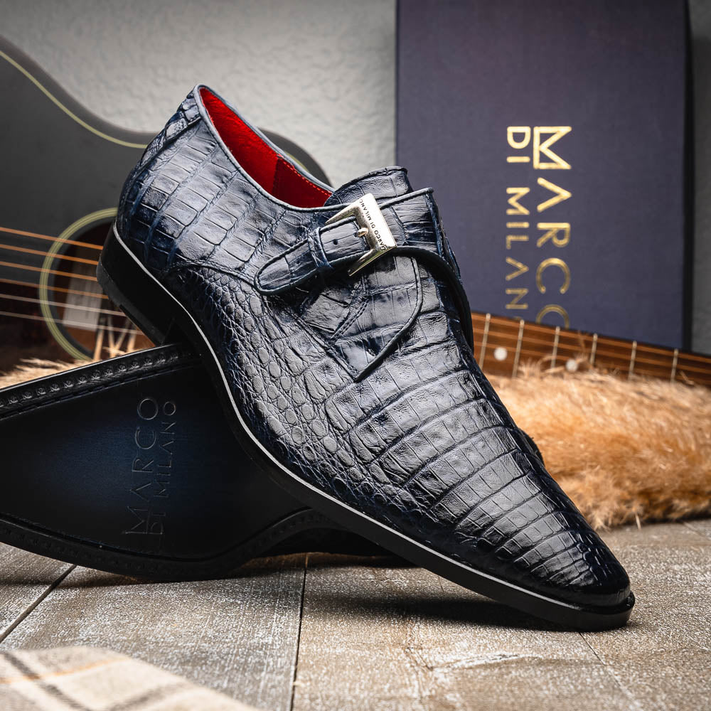 The Marco Di Milano Rovigo Navy features dark blue genuine caiman crocodile monk strap dress shoes with a silver buckle—one upright, the other on its side to display the sole—ideal for luxury men's footwear enthusiasts.