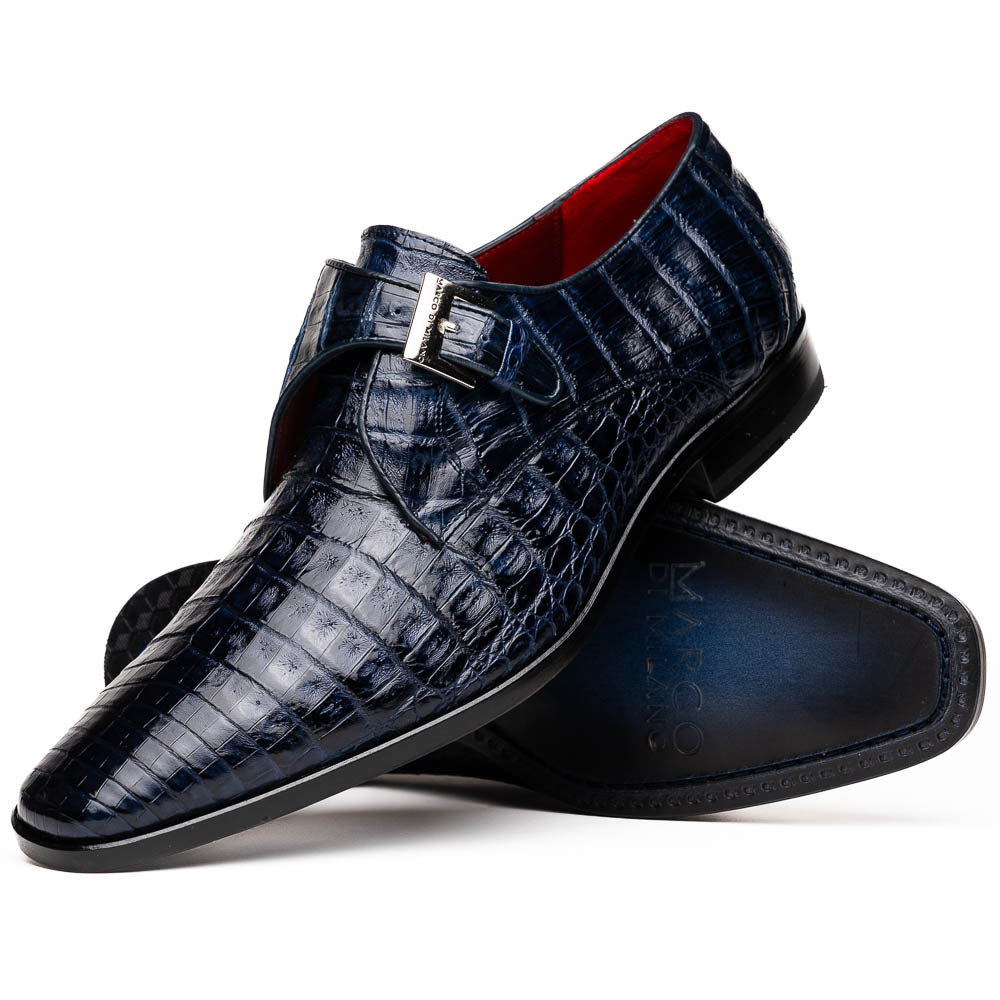 The Marco Di Milano Rovigo Navy features dark blue genuine caiman crocodile monk strap dress shoes with a silver buckle—one upright, the other on its side to display the sole—ideal for luxury men's footwear enthusiasts.
