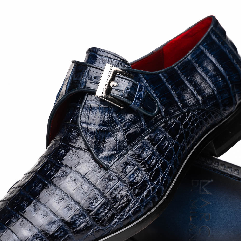 The Marco Di Milano Rovigo Navy features dark blue genuine caiman crocodile monk strap dress shoes with a silver buckle—one upright, the other on its side to display the sole—ideal for luxury men's footwear enthusiasts.