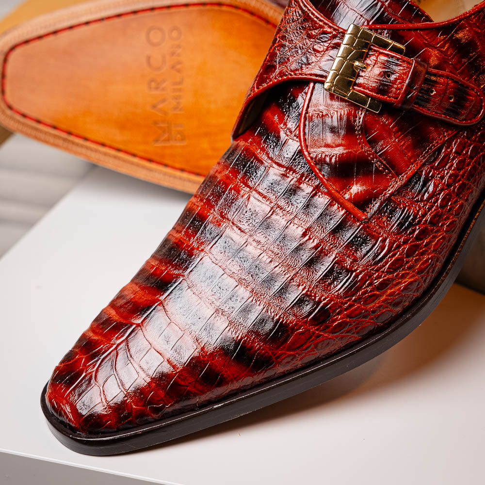The Rovigo Cognac Straps by Marco Di Milano are brown genuine caiman crocodile monk strap dress shoes with a metal buckle—one upright, one on its side showing the branded sole. Luxury footwear for refined taste.