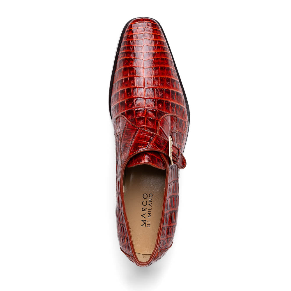 A pair of Rovigo Rustic Cognac monk strap dress shoes by Marco Di Milano, featuring shiny genuine caiman crocodile leather with a side buckle; one shoe is upright, and the other lies with its sole facing up.