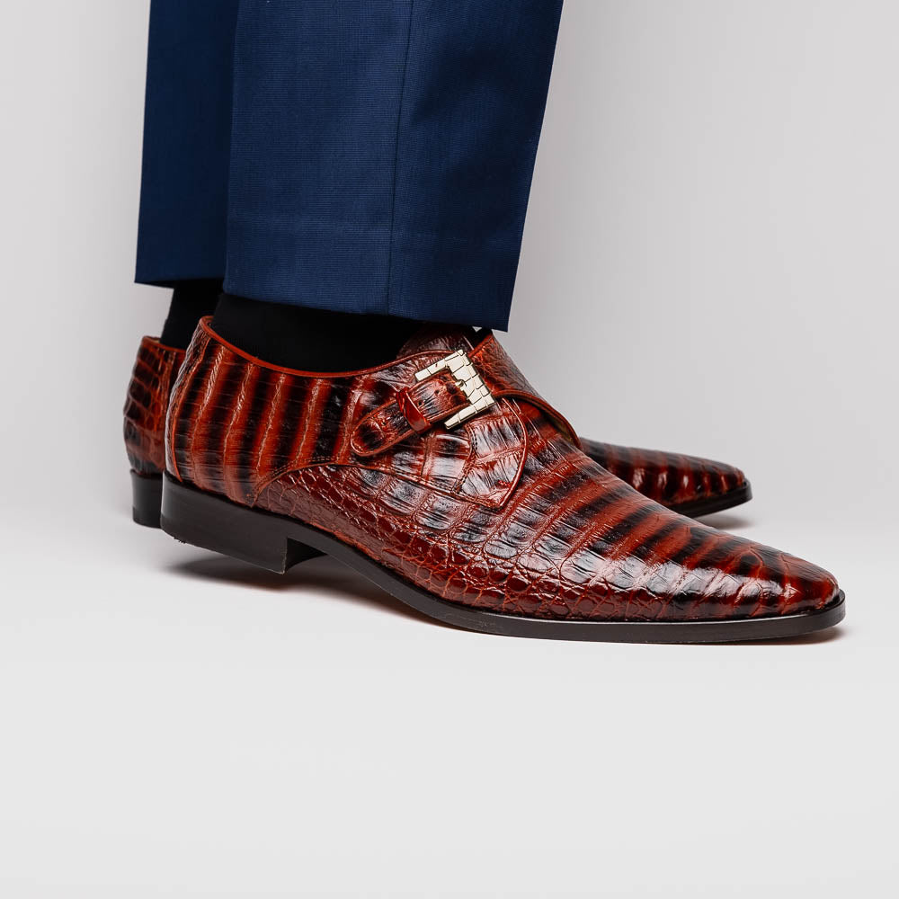 The Rovigo Cognac Straps by Marco Di Milano are brown genuine caiman crocodile monk strap dress shoes with a metal buckle—one upright, one on its side showing the branded sole. Luxury footwear for refined taste.