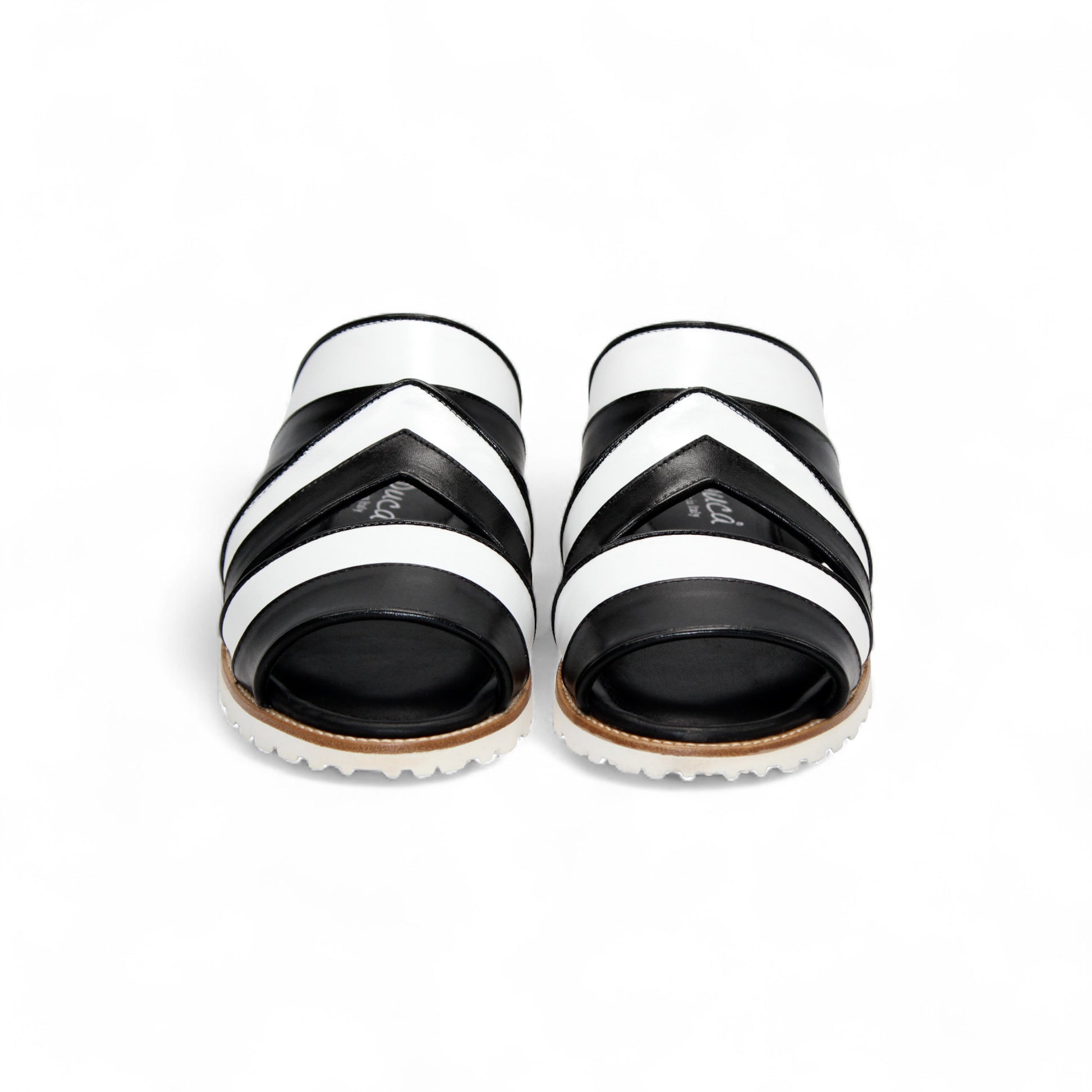 The Duca Di Matiste Duca SA118 Black/White slip-on sandal features crisscross straps and a flat, ridged sole, shown from the side on a white background—showcasing modern Italian-inspired shoe design.