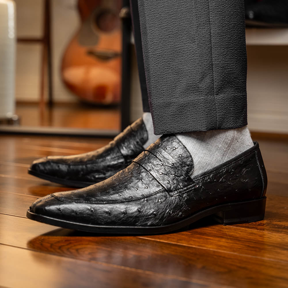 The Salvatore Black by Marco Di Milano is a pair of genuine ostrich leather loafers in black with a brown leather sole, detailed stitching, and an embossed brand logo on the outsole—ideal for luxury footwear enthusiasts.