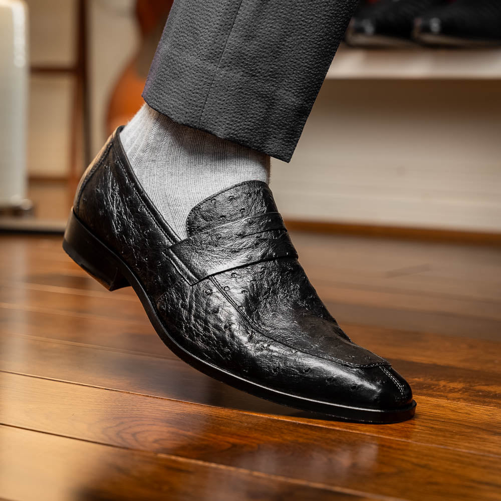 The Salvatore Black by Marco Di Milano is a pair of genuine ostrich leather loafers in black with a brown leather sole, detailed stitching, and an embossed brand logo on the outsole—ideal for luxury footwear enthusiasts.
