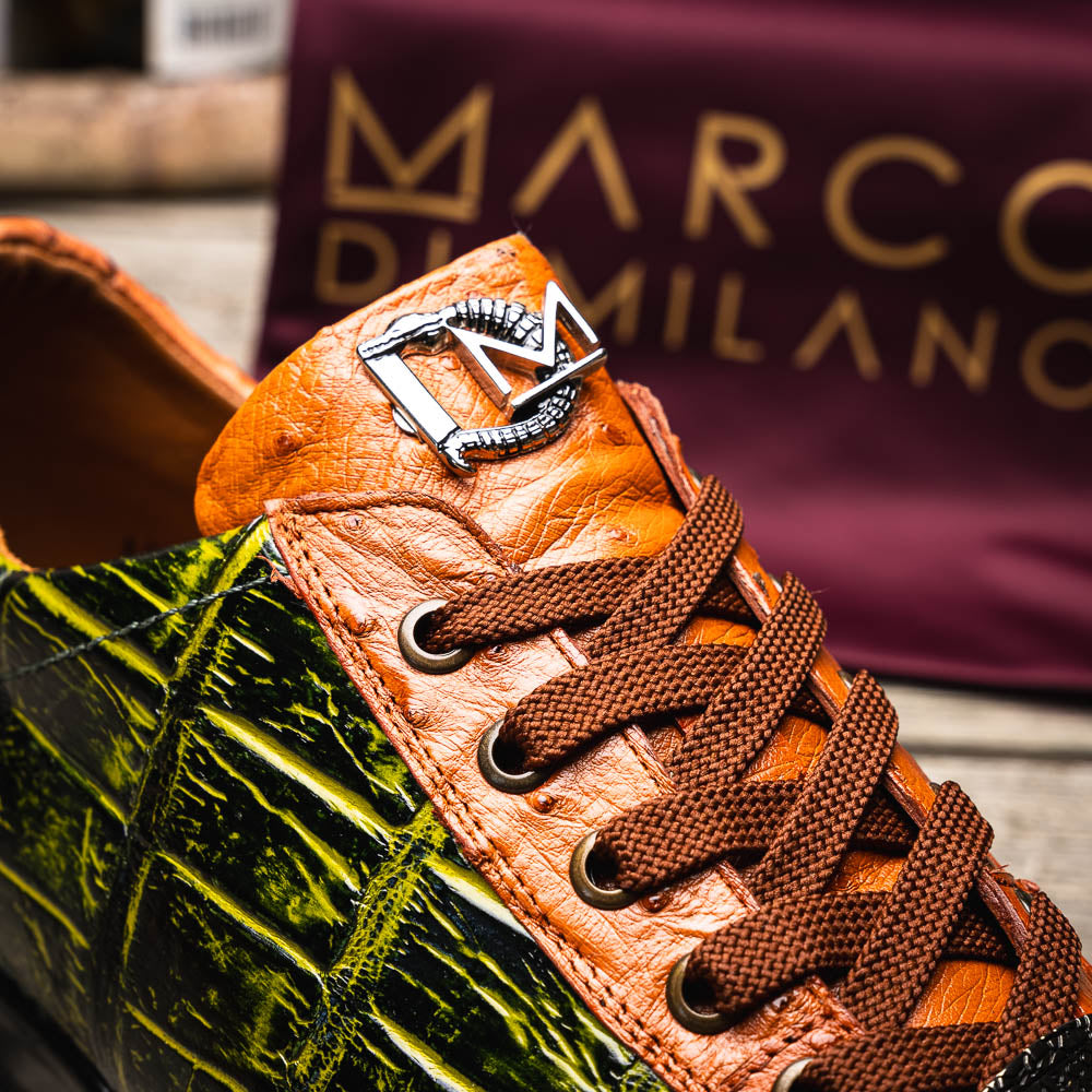 The Saulo Green / Cognac by Marco Di Milano is a luxury men's sneaker with an orange and green crocodile pattern, brown laces, black sole, and metallic tongue emblem—ideal for those wanting an authentic alligator look.