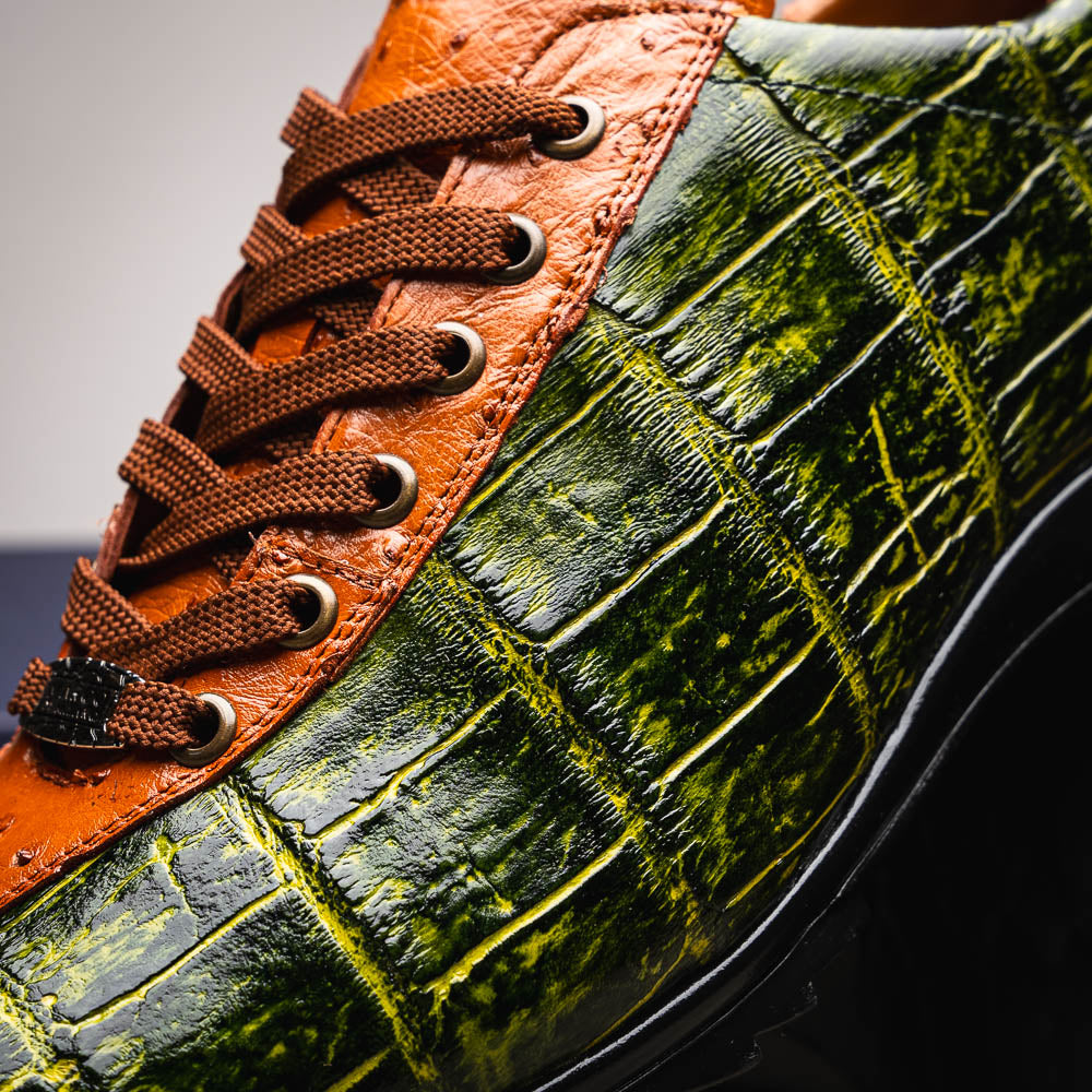 The Saulo Green / Cognac by Marco Di Milano is a luxury men's sneaker with an orange and green crocodile pattern, brown laces, black sole, and metallic tongue emblem—ideal for those wanting an authentic alligator look.
