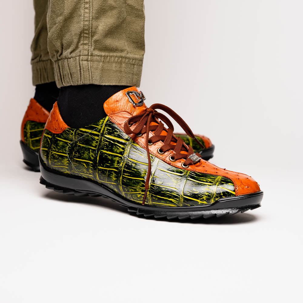 The Saulo Green / Cognac by Marco Di Milano is a luxury men's sneaker with an orange and green crocodile pattern, brown laces, black sole, and metallic tongue emblem—ideal for those wanting an authentic alligator look.
