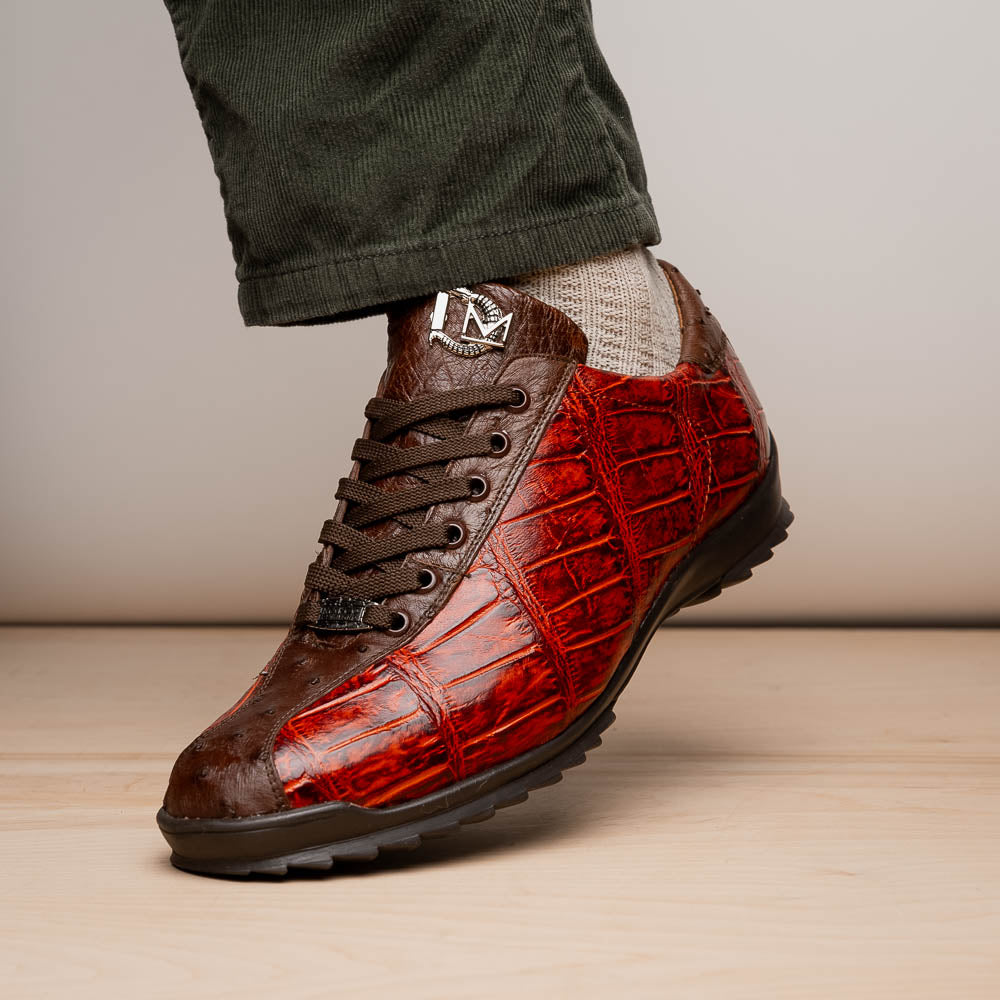 The Saulo Cognac sneakers by Marco Di Milano feature genuine alligator leather in red and brown with black laces and soles—an exceptional luxury men's footwear choice, shown with one upright and the other lying on its side.