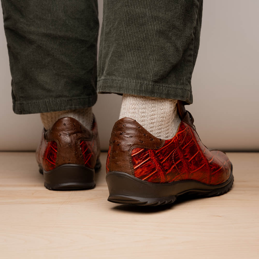 The Saulo Cognac sneakers by Marco Di Milano feature genuine alligator leather in red and brown with black laces and soles—an exceptional luxury men's footwear choice, shown with one upright and the other lying on its side.