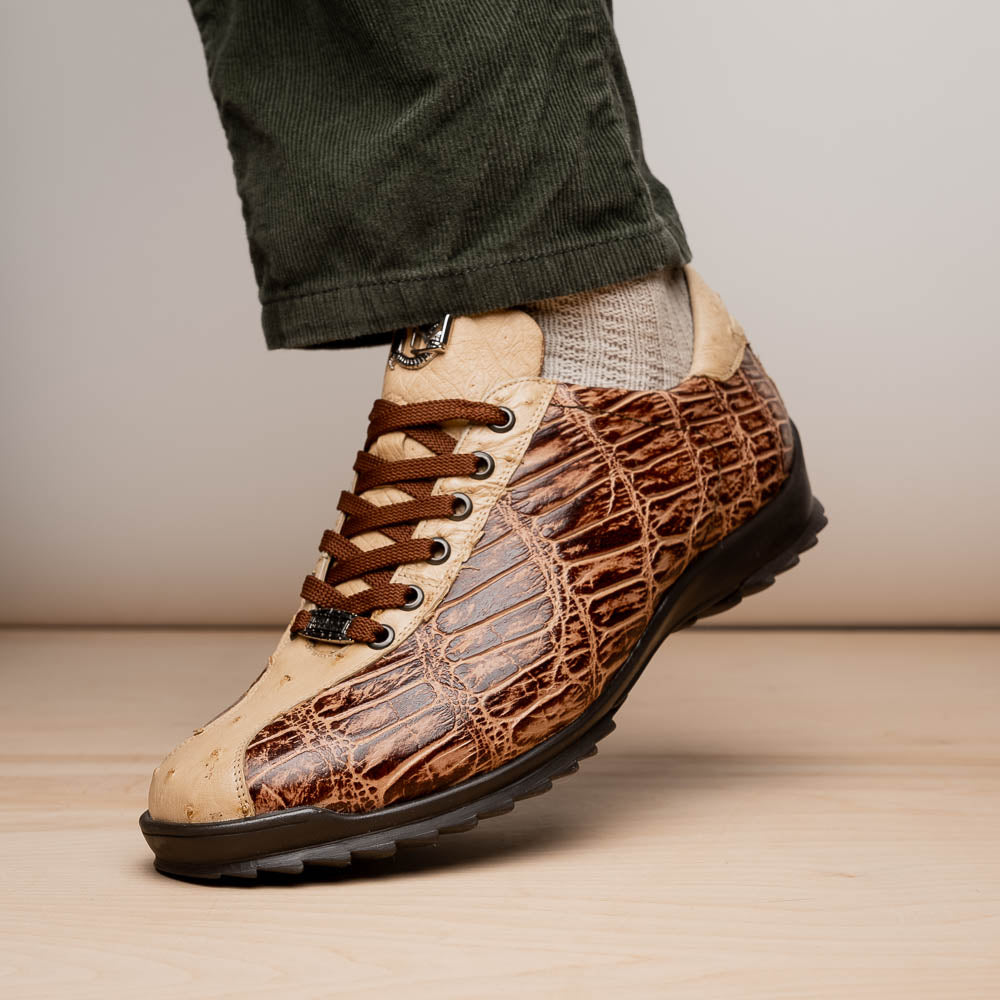 A pair of Saulo Orix men's shoes by Marco Di Milano, featuring brown crocodile-pattern leather and black rubber soles; one shoe stands upright while the other leans against it.