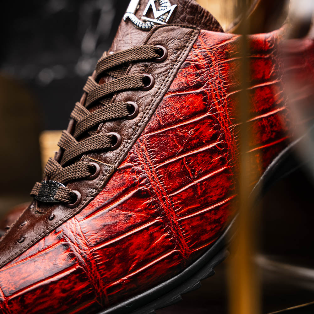 The Saulo Cognac sneakers by Marco Di Milano feature genuine alligator leather in red and brown with black laces and soles—an exceptional luxury men's footwear choice, shown with one upright and the other lying on its side.
