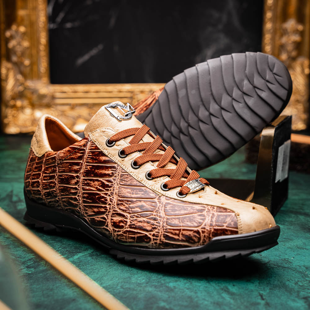 A pair of Saulo Orix men's shoes by Marco Di Milano, featuring brown crocodile-pattern leather and black rubber soles; one shoe stands upright while the other leans against it.