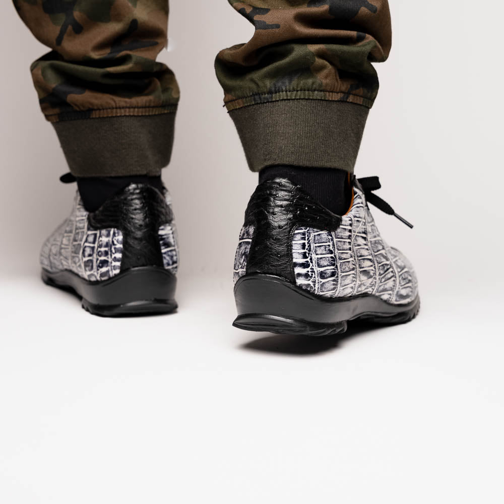 The Saulo Newspaper / Black sneakers by Marco Di Milano are luxury men's shoes featuring a black and white crocodile pattern, black laces, and a textured sole, showcased on a white background.
