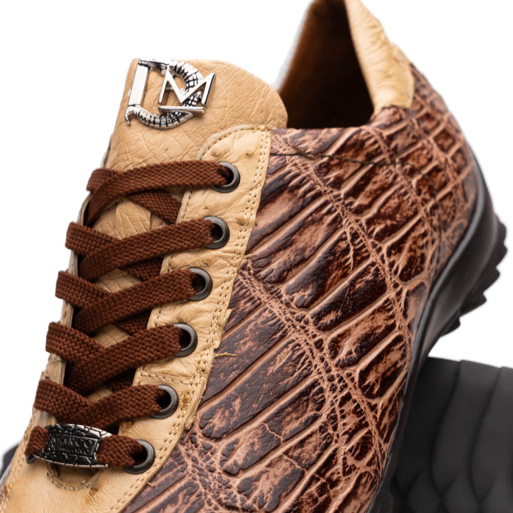 A pair of Saulo Orix men's shoes by Marco Di Milano, featuring brown crocodile-pattern leather and black rubber soles; one shoe stands upright while the other leans against it.