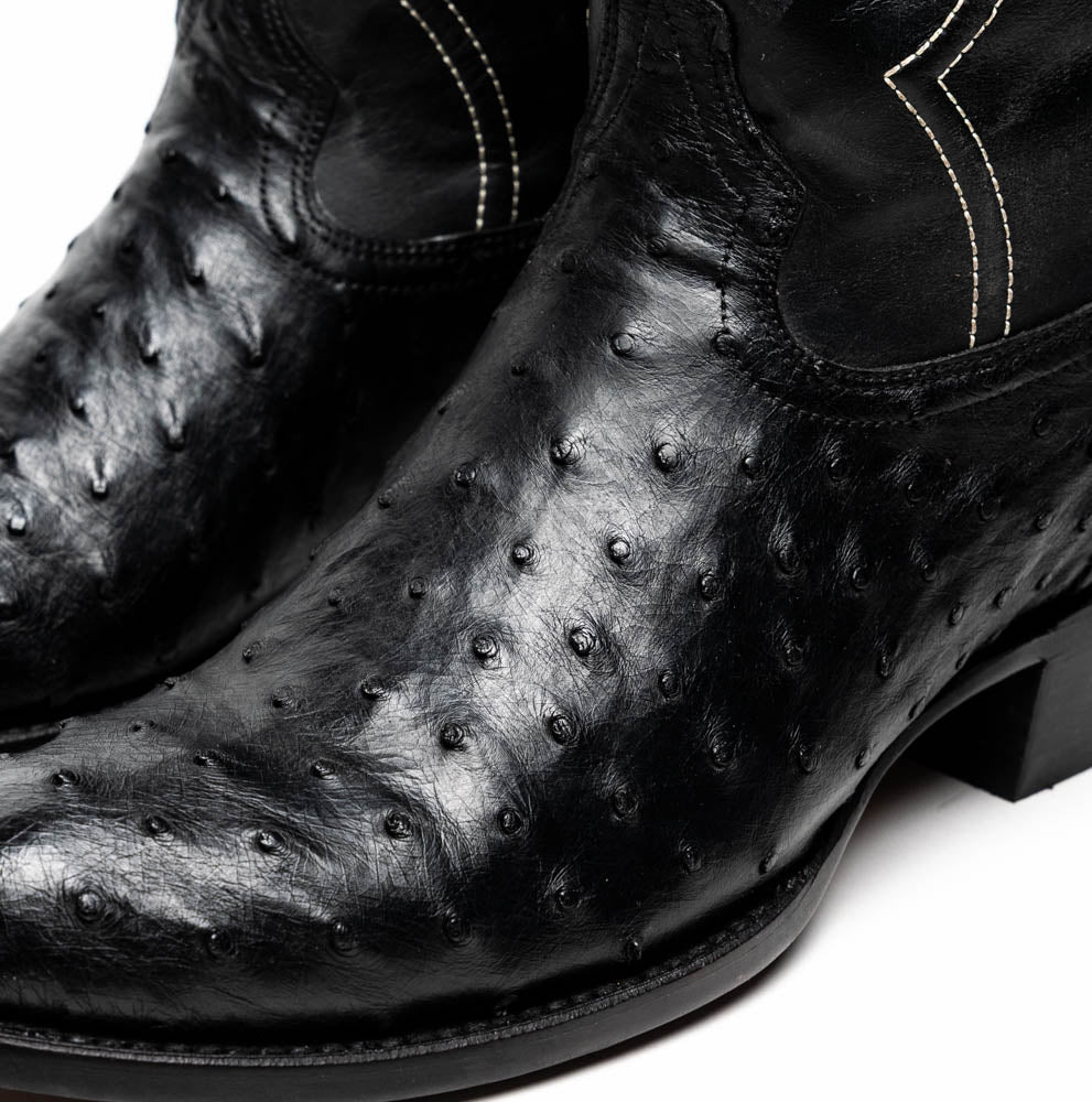 A pair of handcrafted Savannah Black western boots by Marco Di Milano; one boot stands upright while the other lies on its side, displaying a branded sole with "Marco Di Milano.