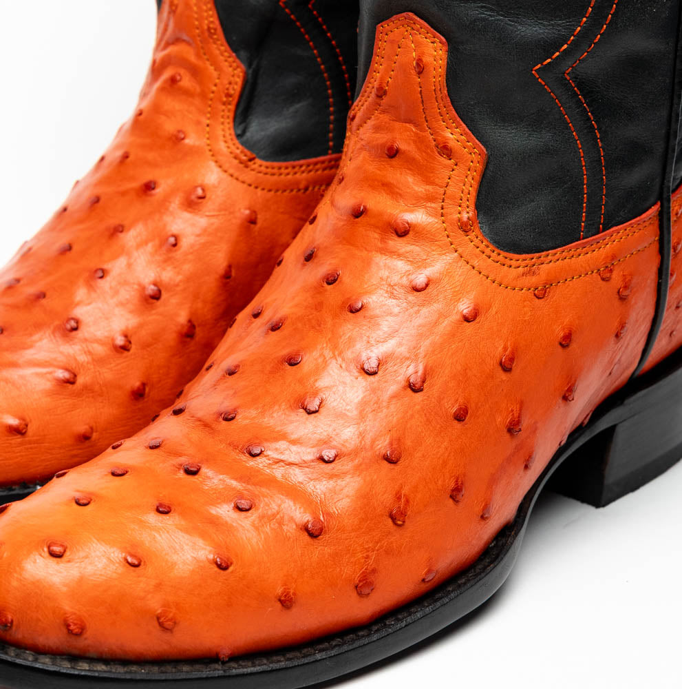 The Savannah Orange boots by Marco Di Milano feature orange ostrich leather lowers, black genuine leather uppers, intricate stitching, and branded soles.