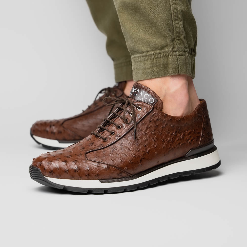 The Scanno Antique Brown sneaker by Marco Di Milano features genuine ostrich quill leather in brown, black laces, and a white-and-black rubber sole. One shoe stands upright while the other rests on its side, highlighting the hand-painted finish.