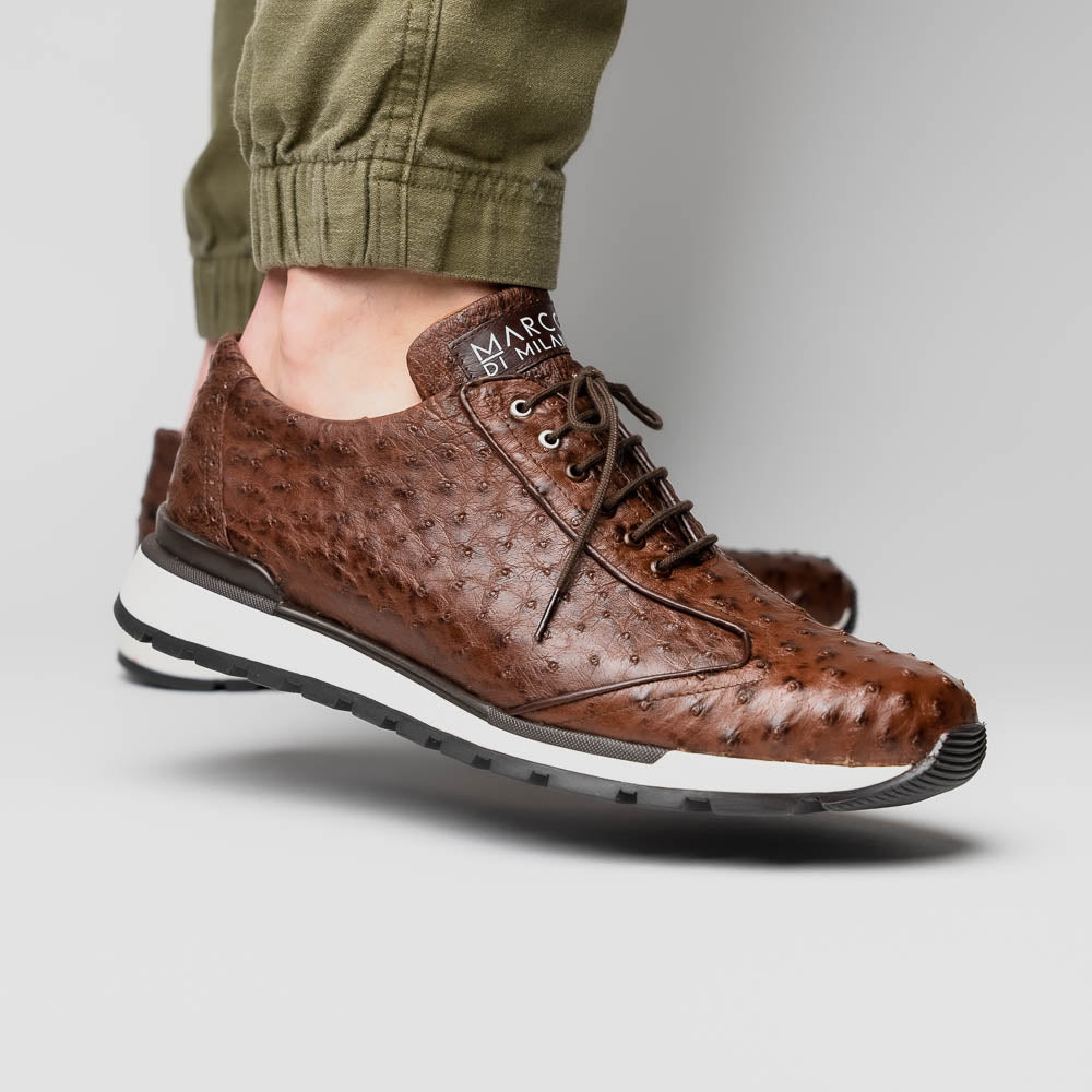 The Scanno Antique Brown sneaker by Marco Di Milano features genuine ostrich quill leather in brown, black laces, and a white-and-black rubber sole. One shoe stands upright while the other rests on its side, highlighting the hand-painted finish.