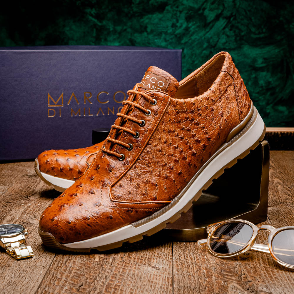 The Scanno Antique Cognac by Marco Di Milano is a brown leather sneaker with an ostrich-patterned, hand-painted finish, white midsole, brown outsole, and brand logo on the tongue—ideal for genuine ostrich quill sneaker fans. Photographed on a plain background.