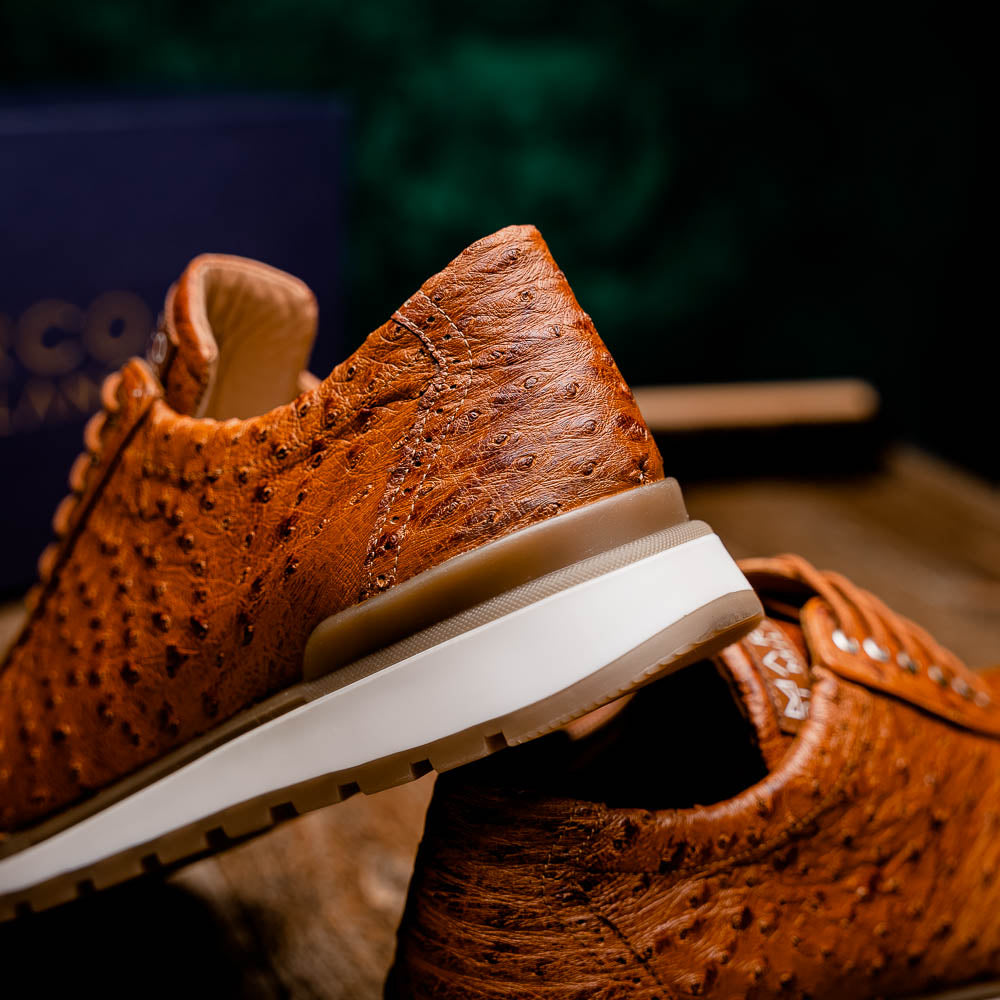 The Scanno Antique Cognac by Marco Di Milano is a brown leather sneaker with an ostrich-patterned, hand-painted finish, white midsole, brown outsole, and brand logo on the tongue—ideal for genuine ostrich quill sneaker fans. Photographed on a plain background.