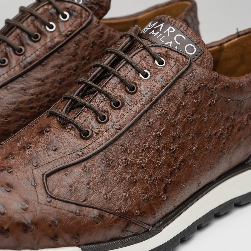 The Scanno Antique Brown sneaker by Marco Di Milano features genuine ostrich quill leather in brown, black laces, and a white-and-black rubber sole. One shoe stands upright while the other rests on its side, highlighting the hand-painted finish.