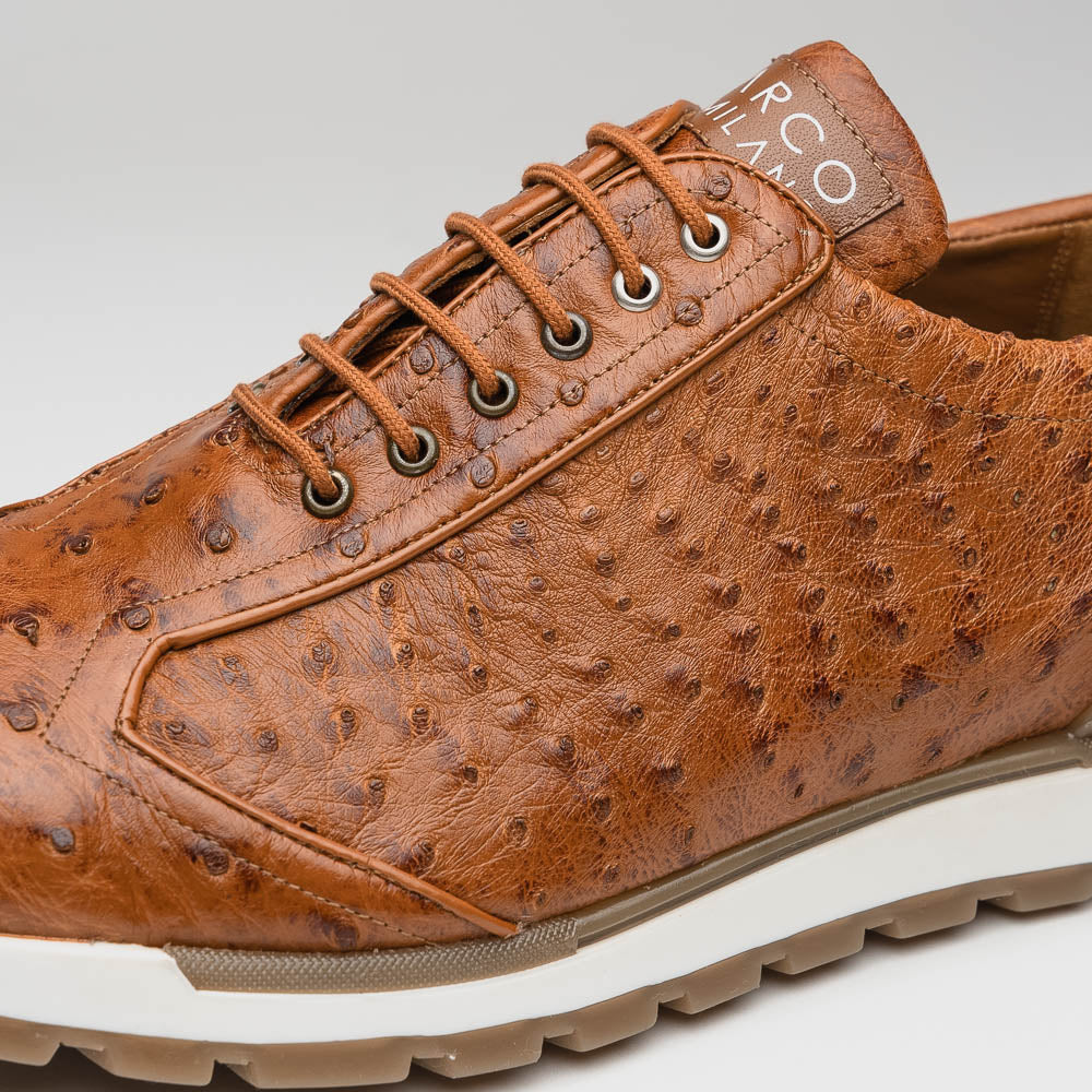 The Scanno Antique Cognac by Marco Di Milano is a brown leather sneaker with an ostrich-patterned, hand-painted finish, white midsole, brown outsole, and brand logo on the tongue—ideal for genuine ostrich quill sneaker fans. Photographed on a plain background.