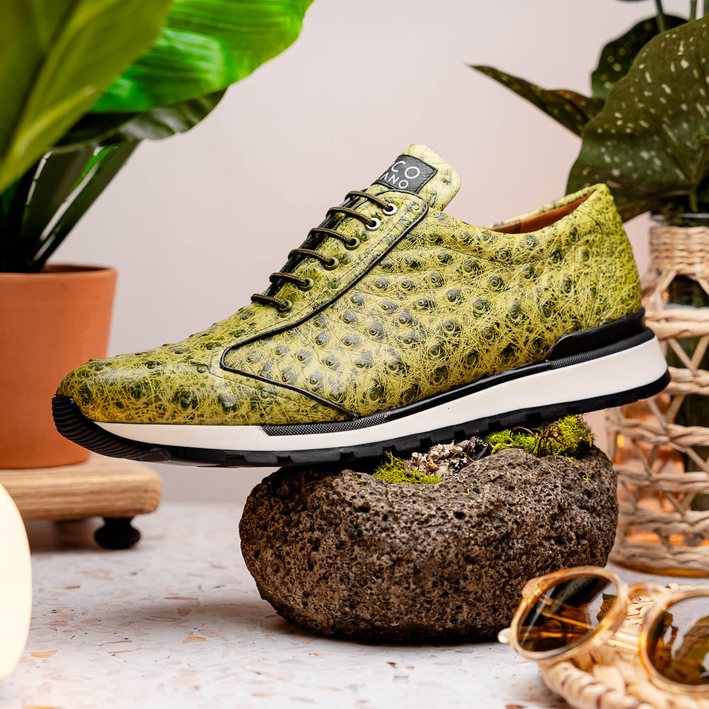 The Marco Di Milano Scanno Antique Green sneakers feature textured genuine ostrich quill in green, black laces, and white soles, with one shoe upright and the other propped beneath—exuding luxury footwear style.